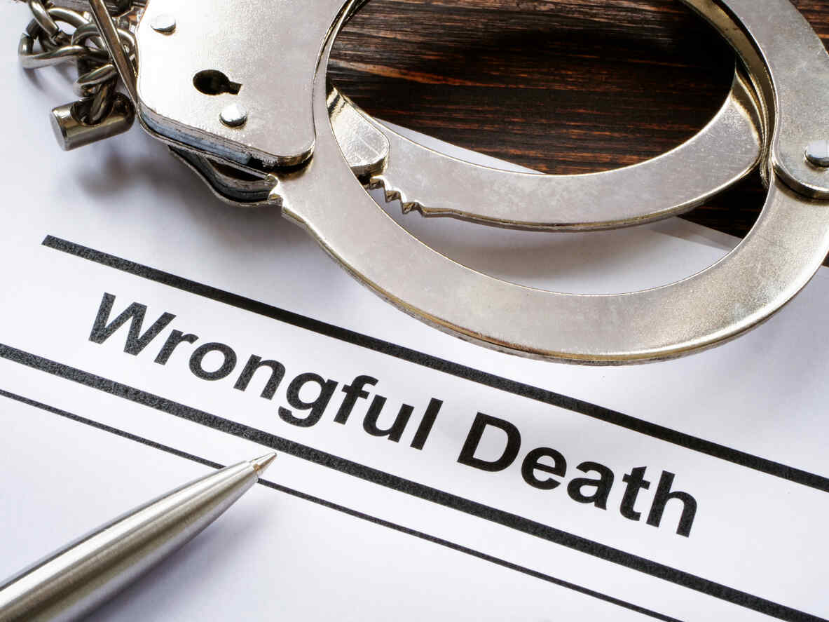 Close-up of handcuffs resting on a document titled 'Wrongful Death' with a pen, symbolizing a wrongful death legal case.